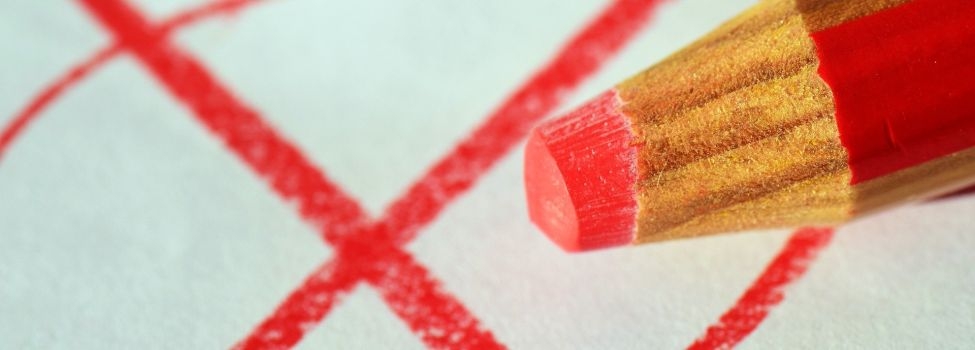 Angekreuzter Wahlzettel und roter Buntstift.