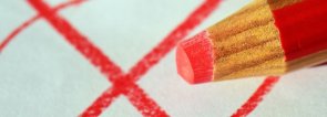 Angekreuzter Wahlzettel und roter Buntstift.