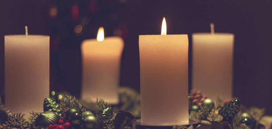 Adventsgesteck mit zwei brennenden Kerzen